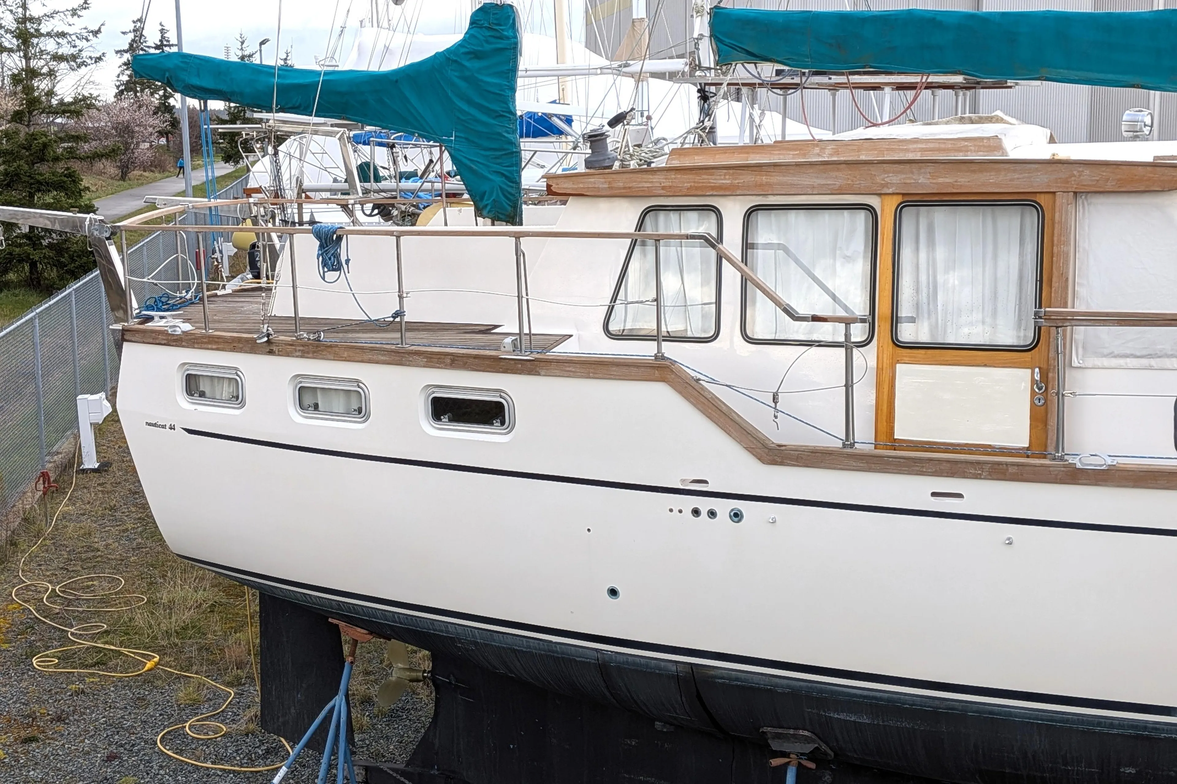 1985 Siltala Nauticat 44 sailboat on land, featuring wooden accents and teal sail covers.