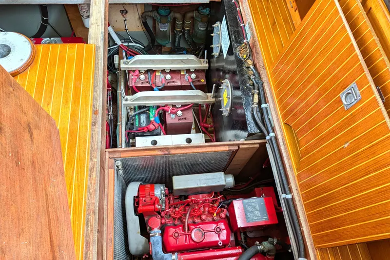 Firefly Yacht Photos Pics Engine compartment of a 1985 Siltala Nauticat 44 sailboat, showcasing red machinery and wooden paneling.