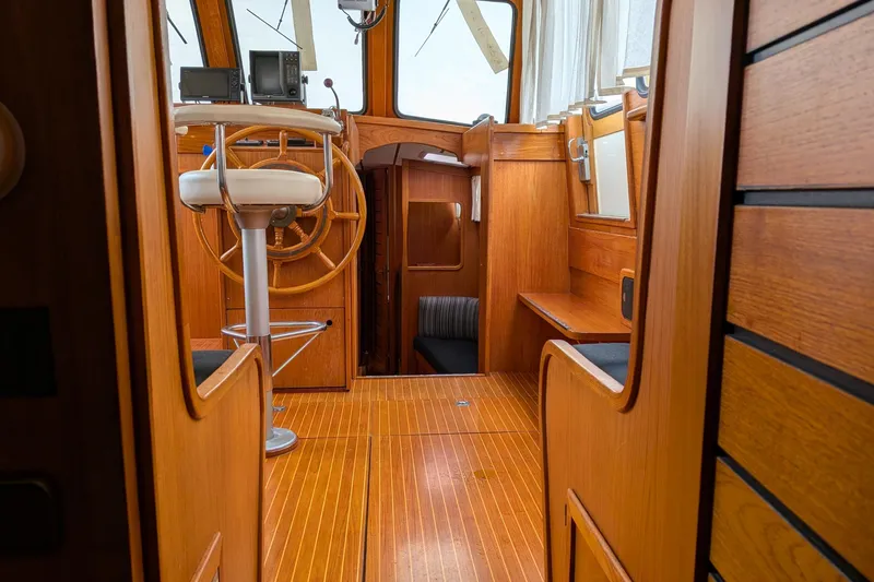 Firefly Yacht Photos Pics Interior of 1985 Siltala Nauticat 44 sailboat with wooden helm and seating area.
