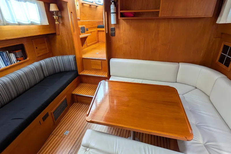 Firefly Yacht Photos Pics Interior of 1985 Siltala Nauticat 44 yacht with wooden table and cushioned seating.