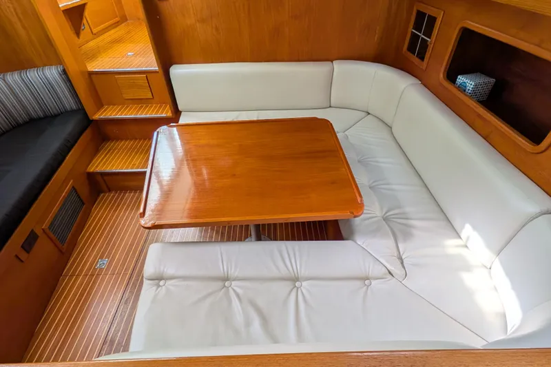 Firefly Yacht Photos Pics Interior of 1985 Siltala Nauticat 44 yacht with wooden table and white seating.