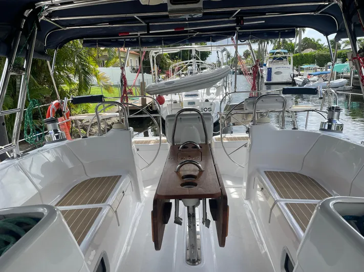 Sailing Diver Yacht Photos Pics Aft cockpit of 2010 Hunter 49 sailboat, featuring seating and steering wheel, docked at marina.