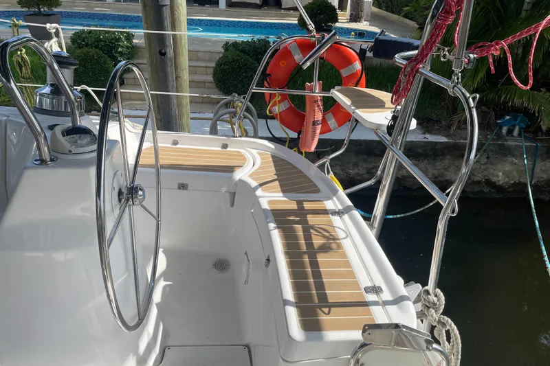 Sailing Diver Yacht Photos Pics 2010 Hunter 49 Aft Cockpit sailboat with steering wheel and lifebuoy, docked near water.