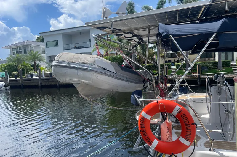 Sailing Diver Yacht Photos Pics Hunter 49 Aft Cockpit 2010 yacht with dinghy and solar panels docked by waterfront homes.