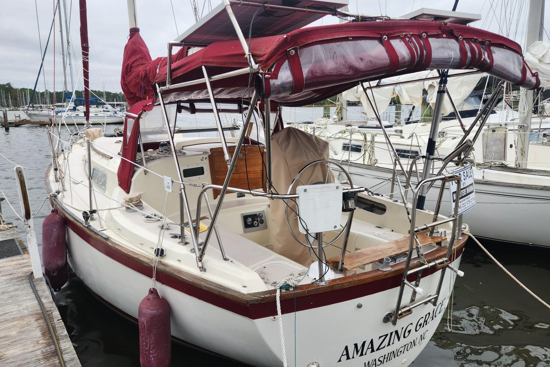 1982 Pearson 323 sailboat docked, featuring maroon canvas and "Amazing Grace" on the stern.