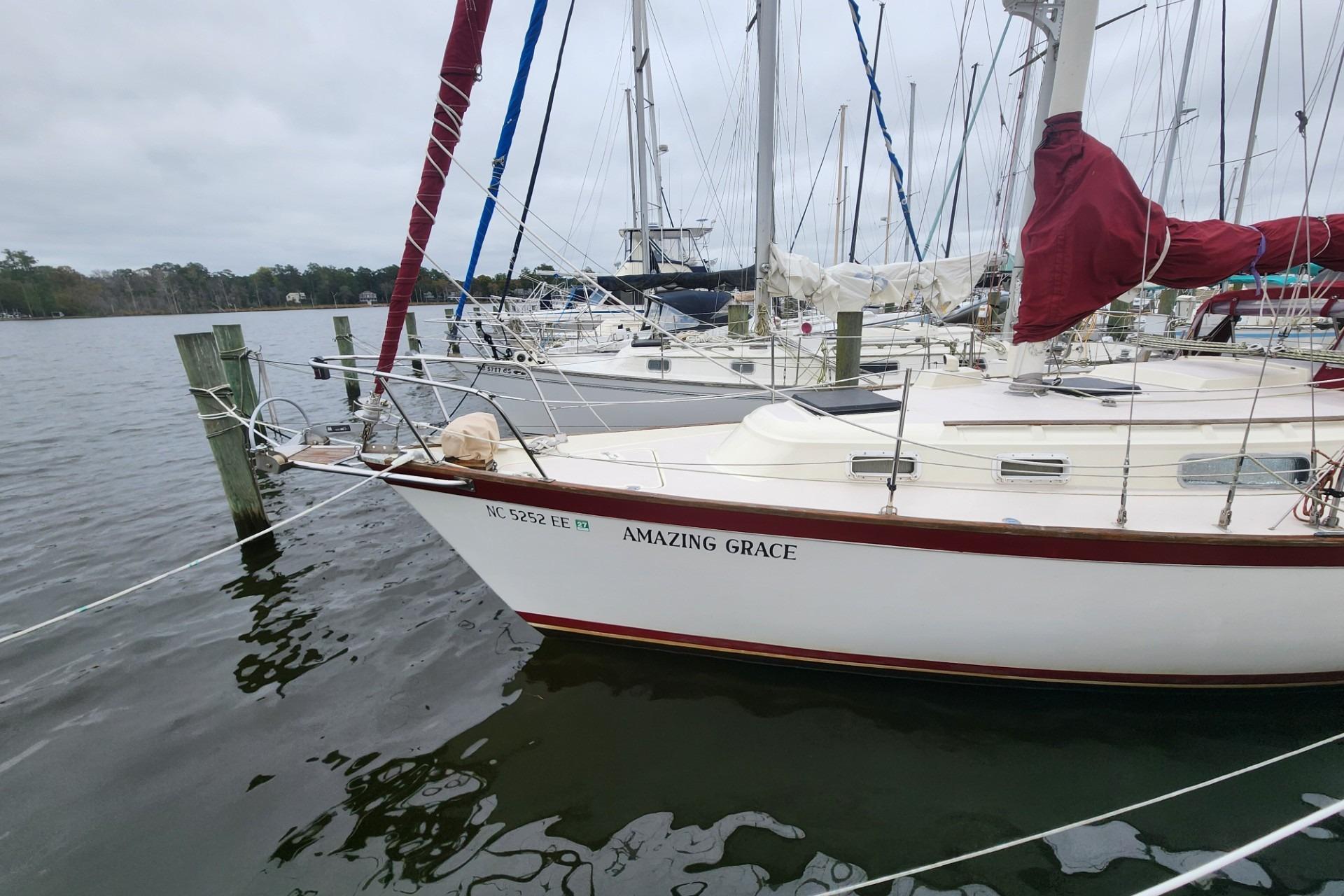 1982 Pearson 323 sailboat "Amazing Grace" docked at marina, overcast sky.