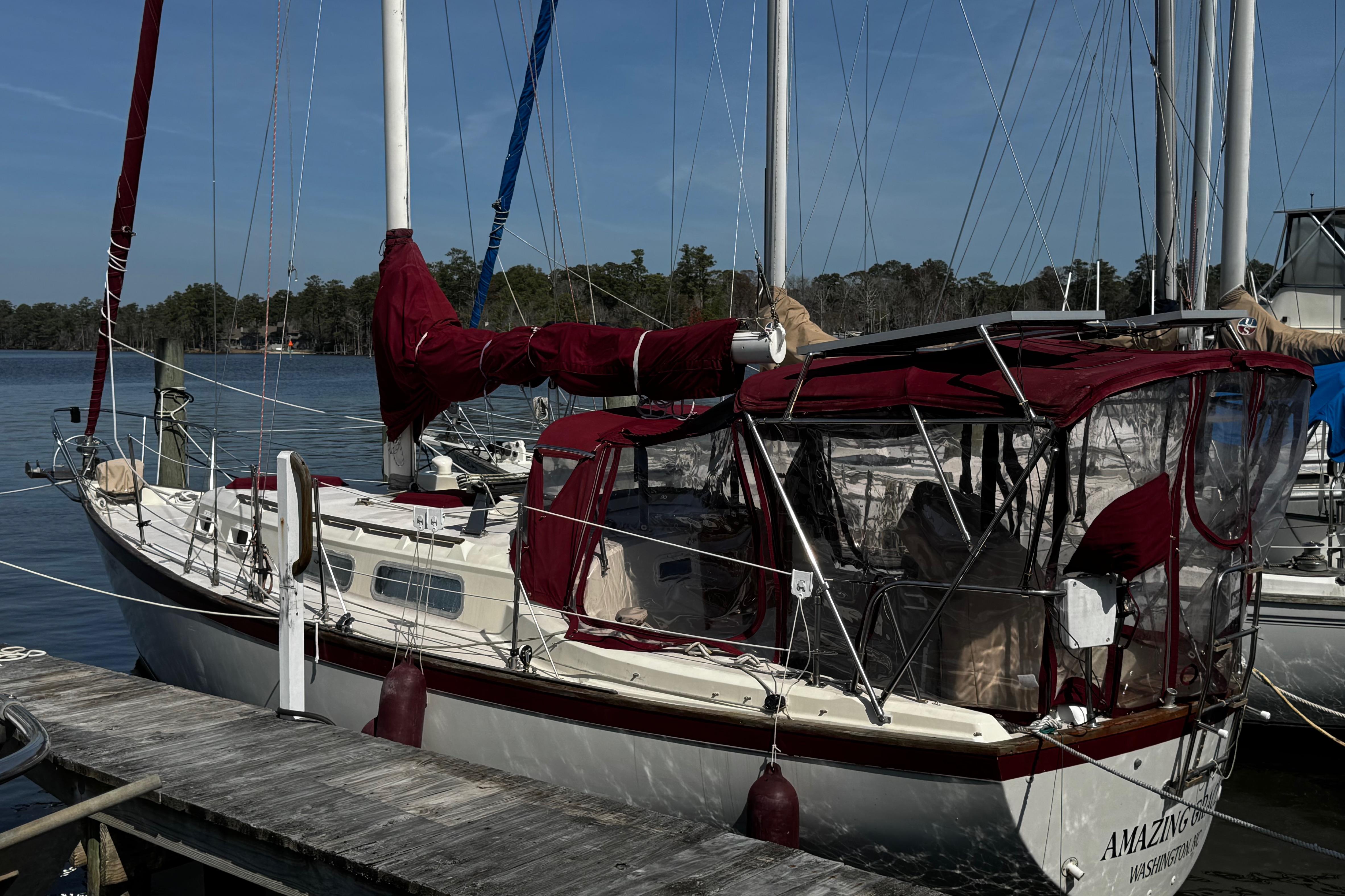 1982 Pearson 323 sailboat docked with red canvas covers and clear enclosures.