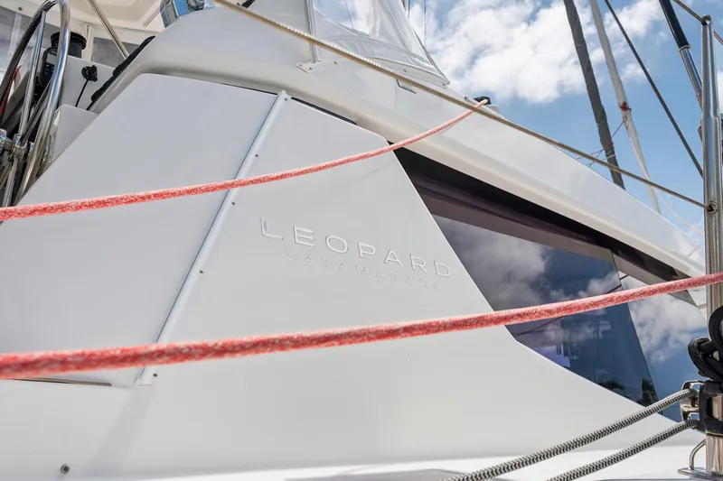 Always Wet Yacht Photos Pics 2021 Leopard 45 catamaran with sleek design and red ropes against a blue sky.