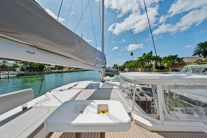 Always Wet Yacht Photos Pics 2021 Leopard 45 catamaran deck with seating, docked in a sunny marina.