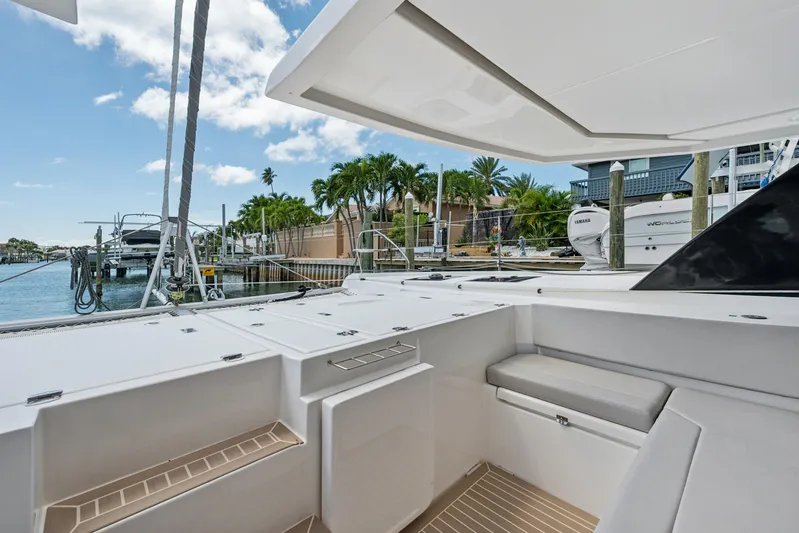 Always Wet Yacht Photos Pics 2021 Leopard 45 yacht deck with seating, docked near palm trees and water.