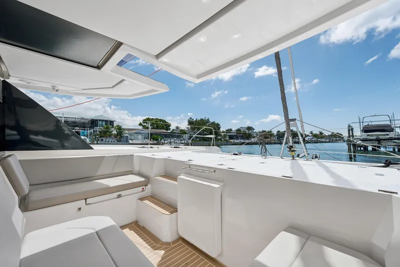 Always Wet Yacht Photos Pics Modern Leopard 45 catamaran interior with seating, docked by a scenic waterfront, 2021 model.