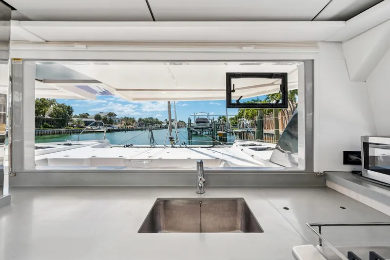 Always Wet Yacht Photos Pics Interior view from a 2021 Leopard 45 yacht, showcasing a sleek kitchen and scenic marina.