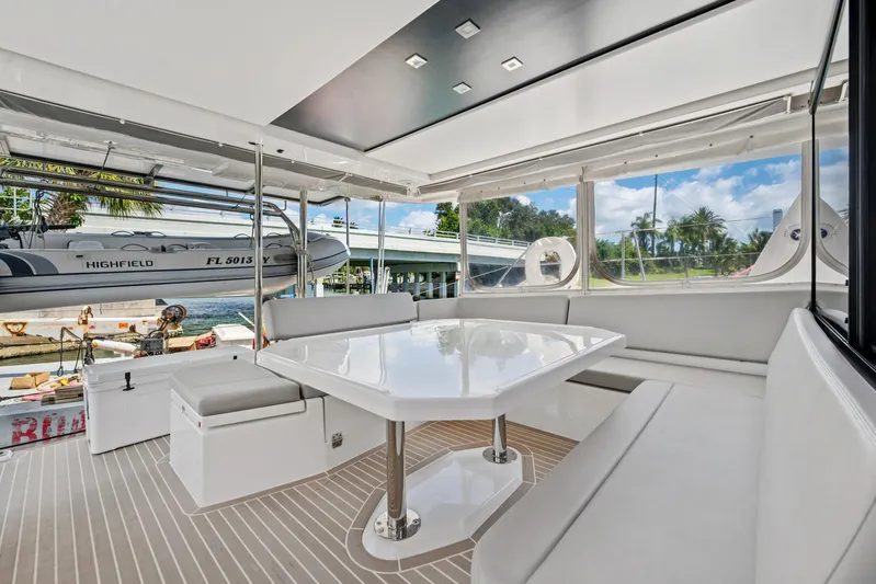 Always Wet Yacht Photos Pics Luxurious 2021 Leopard 45 yacht interior with sleek seating and table, docked near a scenic waterfront.