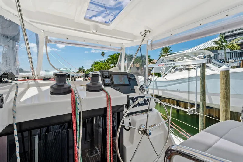Always Wet Yacht Photos Pics Leopard 45 catamaran helm with navigation equipment, ropes, and steering wheel, docked in marina.