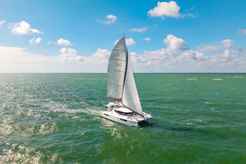 Always Wet Yacht Photos Pics 2021 Leopard 45 sailing catamaran on open sea under clear blue sky.