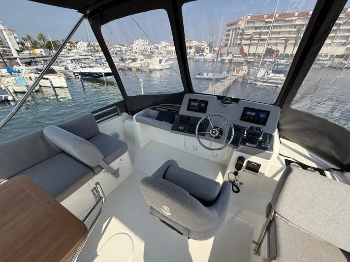 Cassiopee Yacht Photos Pics 2023 Beneteau Swift Trawler 41 Fly cockpit with marina view, featuring modern controls and seating.