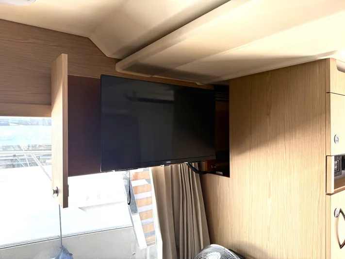 Cassiopee Yacht Photos Pics 2023 Beneteau Swift Trawler 41 Fly interior with mounted TV and wooden cabinetry.