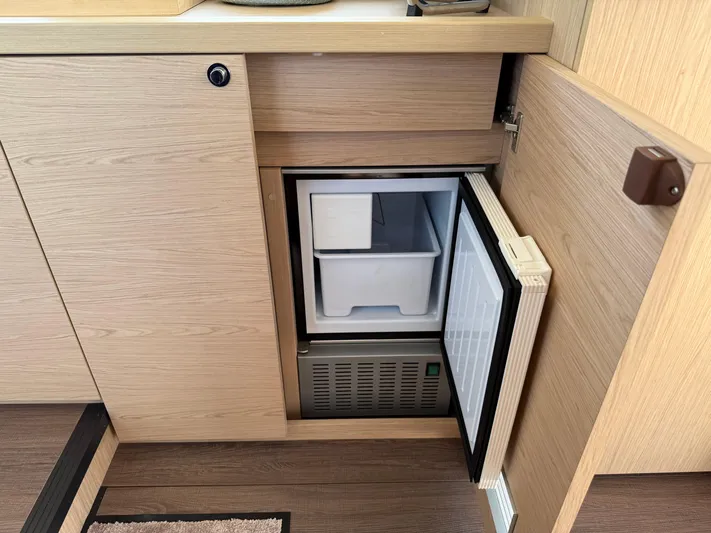 Cassiopee Yacht Photos Pics 2023 Beneteau Swift Trawler 41 Fly interior with open mini fridge in wooden cabinetry.