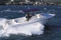2002 Quer 32 Fish Cuddy boat navigating choppy waters with scenic coastal backdrop.