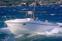 2002 Quer 32 Fish Cuddy boat navigating choppy waters with scenic coastal backdrop.