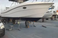2002 Quer 32 Fish Cuddy boat on dry dock, supported by stands, in a marina setting.