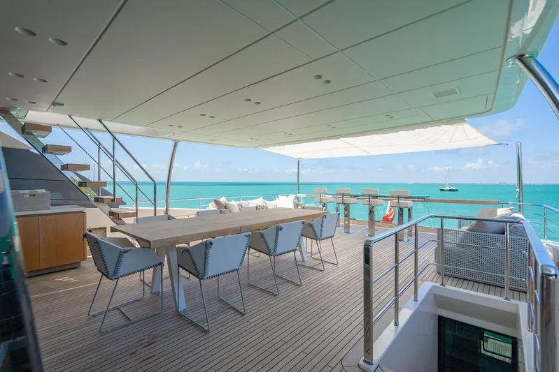 The Wolf Yacht Photos Pics Luxurious 2023 Sanlorenzo SD118 yacht deck with dining area, overlooking turquoise ocean waters.