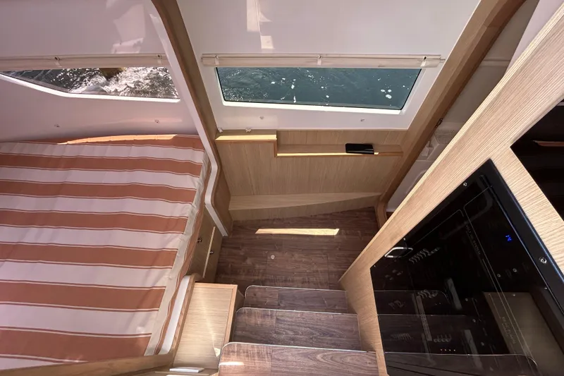  Yacht Photos Pics Interior of 2020 Aquila 36 Sport yacht with striped bedding and wooden finishes.