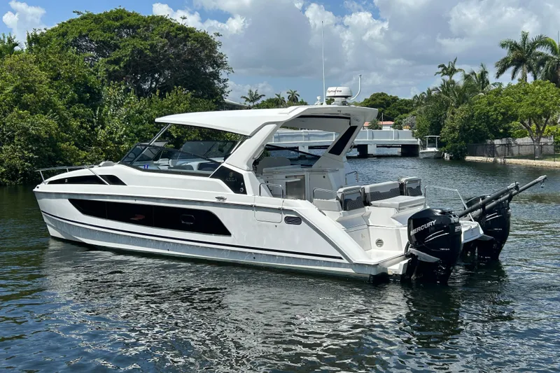  Yacht Photos Pics 2020 Aquila 36 Sport boat on a calm waterway, surrounded by lush greenery.