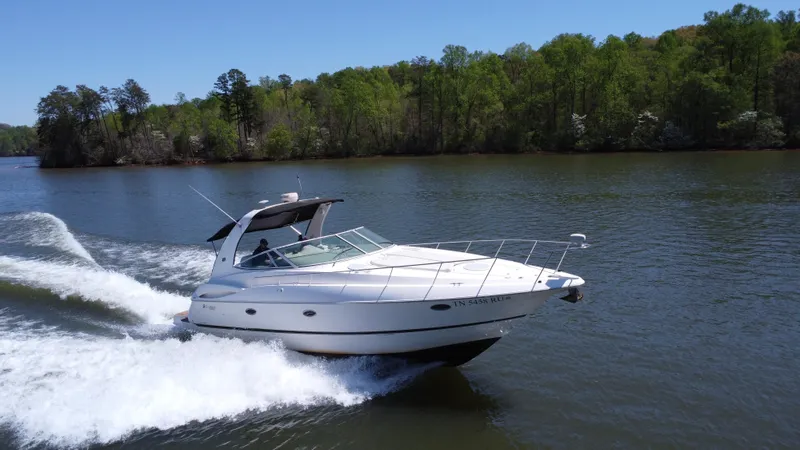  Yacht Photos Pics 2004 Cruisers Yachts 370 Express cruising on a scenic lake with lush green trees.