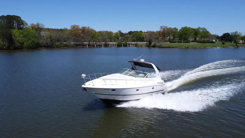  Yacht Photos Pics 2004 Cruisers Yachts 370 Express speeding on a serene lake under clear blue skies.