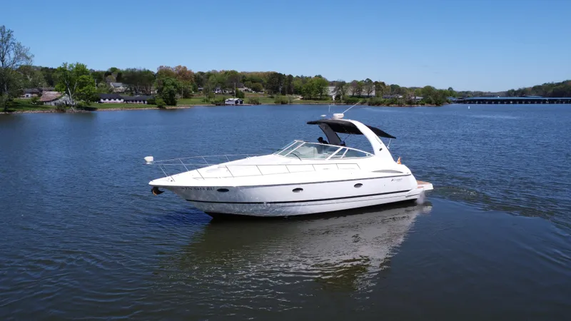  Yacht Photos Pics 2004 Cruisers Yachts 370 Express on a serene lake with lush green shoreline.