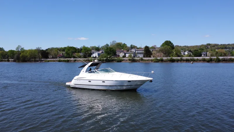  Yacht Photos Pics 2004 Cruisers Yachts 370 Express on calm water with scenic shoreline background.