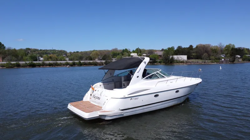  Yacht Photos Pics 2004 Cruisers Yachts 370 Express on a serene lake under a clear blue sky.