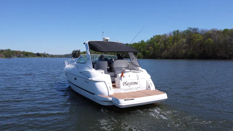  Yacht Photos Pics 2004 Cruisers Yachts 370 Express on a serene lake, surrounded by lush greenery.