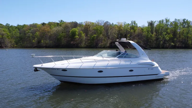  Yacht Photos Pics 2004 Cruisers Yachts 370 Express on a serene lake with lush green trees.