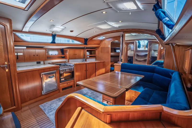 "champagne" Yacht Photos Pics Luxurious interior of 2003 Jeanneau Sun Odyssey 45.2 yacht with wood finish and blue seating.