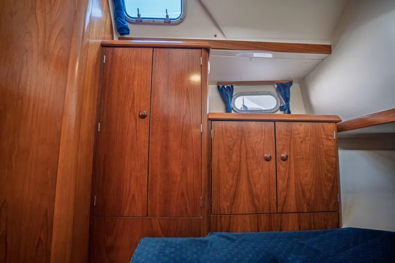 "champagne" Yacht Photos Pics Interior cabin of 2003 Jeanneau Sun Odyssey 45.2 with wooden cabinetry and blue curtains.