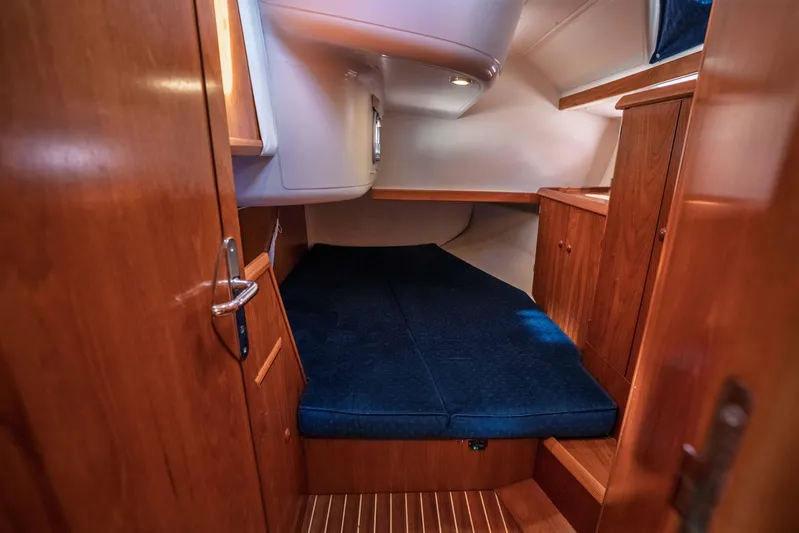 "champagne" Yacht Photos Pics Cozy cabin interior of 2003 Jeanneau Sun Odyssey 45.2 with wooden finish and blue bedding.