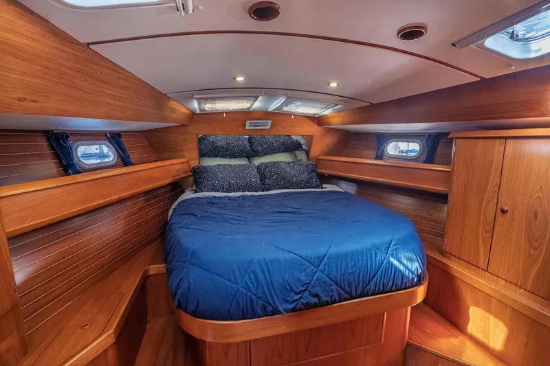 "champagne" Yacht Photos Pics Cozy cabin interior of 2003 Jeanneau Sun Odyssey 45.2 with wooden finish and blue bedding.