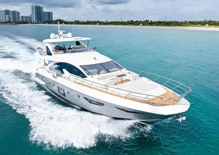Deep Blue Yacht Photos Pics 2018 Azimut Flybridge yacht cruising on turquoise waters near a city skyline.