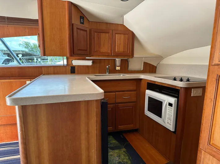  Yacht Photos Pics 2003 Luhrs 40 Convertible yacht kitchen with wood cabinetry, countertop, microwave, and stove.