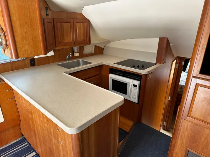  Yacht Photos Pics 2003 Luhrs 40 Convertible yacht kitchen with wood cabinetry, sink, stove, and microwave.