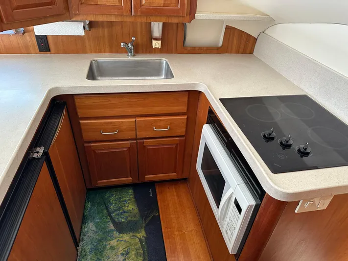  Yacht Photos Pics 2003 Luhrs 40 Convertible kitchen with sink, stove, microwave, and wooden cabinetry.