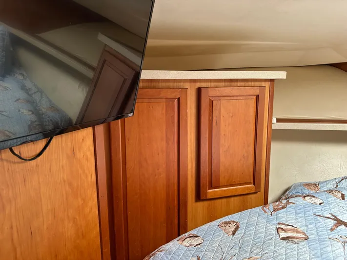  Yacht Photos Pics 2003 Luhrs 40 Convertible interior with wood cabinets, TV, and patterned bedding.