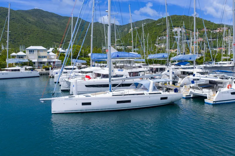 Heartbeat Yacht Photos Pics 2024 Beneteau Oceanis Yacht 54 docked in a scenic marina with lush hills.