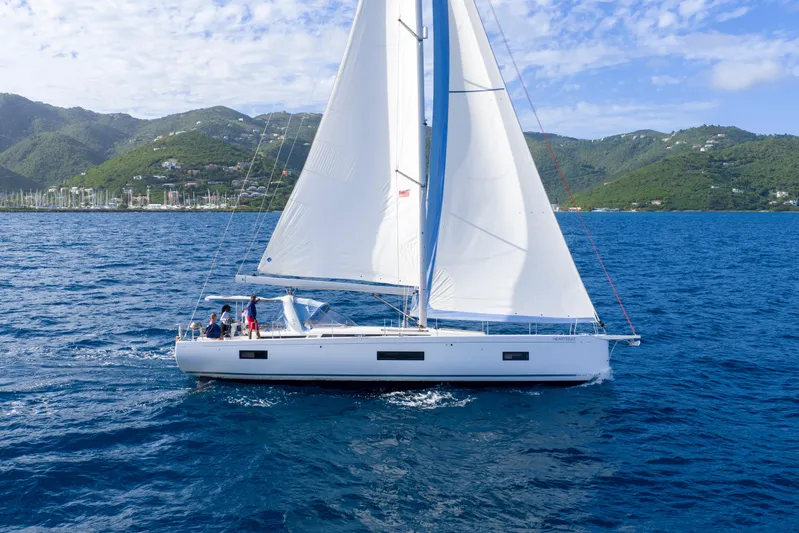 Heartbeat Yacht Photos Pics 2024 Beneteau Oceanis Yacht 54 sailing on blue ocean with scenic mountain backdrop.