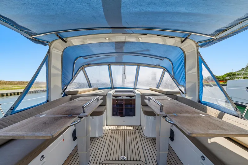 Heartbeat Yacht Photos Pics 2024 Beneteau Oceanis Yacht 54 cockpit with blue canopy and wooden seating area.