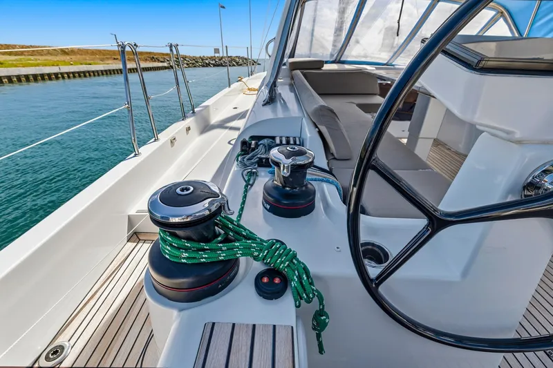 Heartbeat Yacht Photos Pics 2024 Beneteau Oceanis Yacht 54 deck with steering wheel and winches, docked by calm waters.