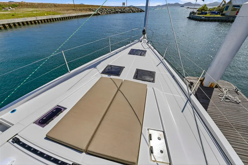 Heartbeat Yacht Photos Pics 2024 Beneteau Oceanis Yacht 54 deck with sunbathing area, docked in a scenic marina.