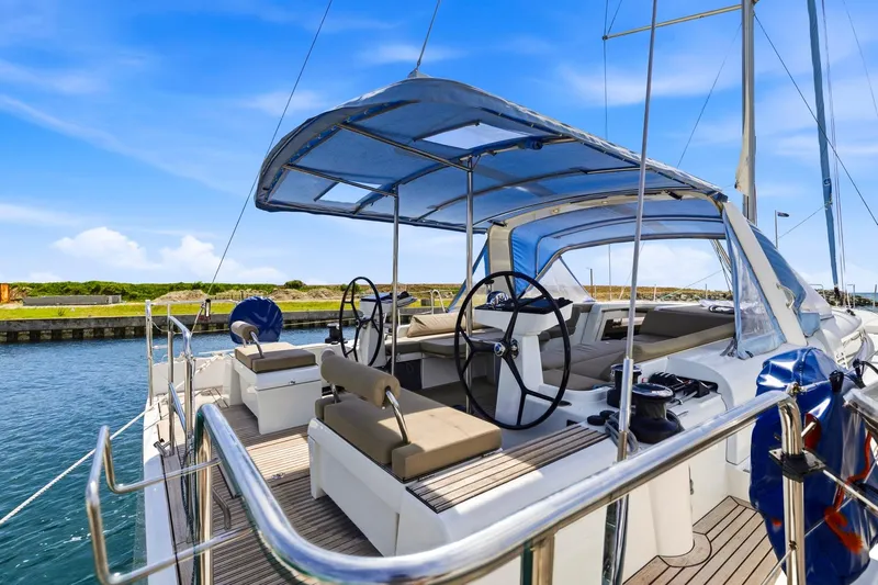 Heartbeat Yacht Photos Pics 2024 Beneteau Oceanis Yacht 54, elegant deck view, dual steering wheels, sunny marina backdrop.